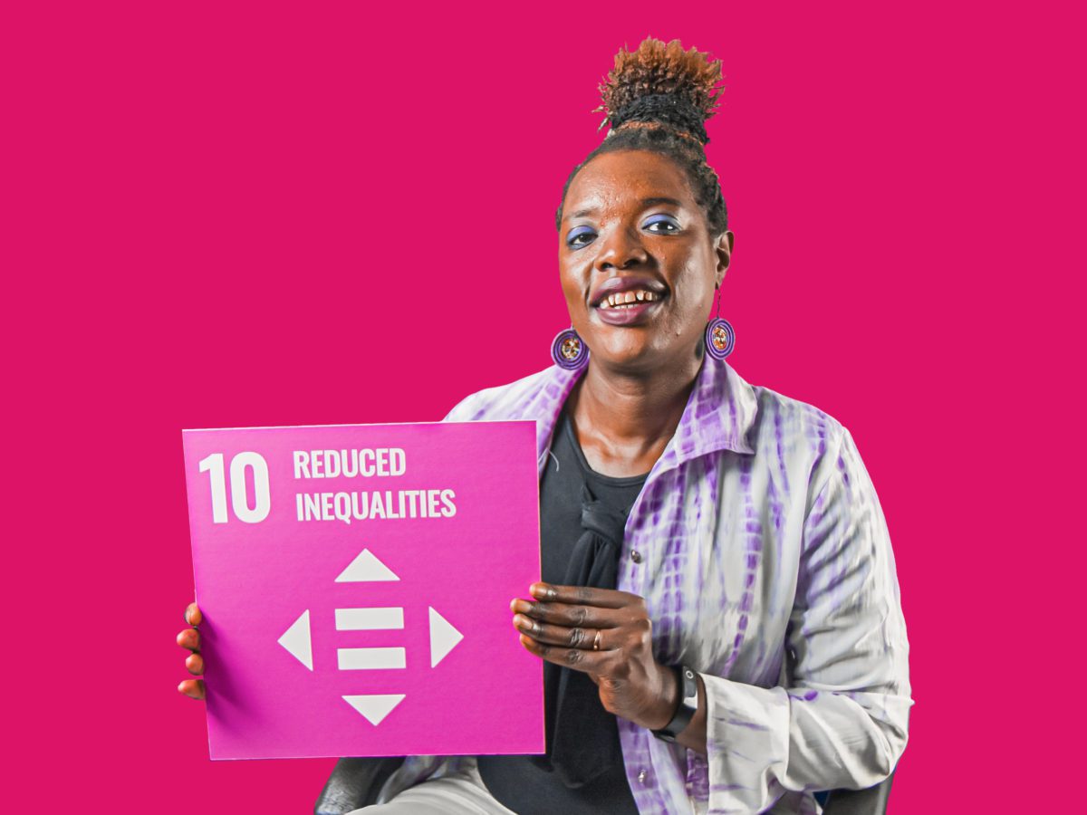 Woman holding up sign showing Global Sustainable Development Goal 10, reduced inequalities.