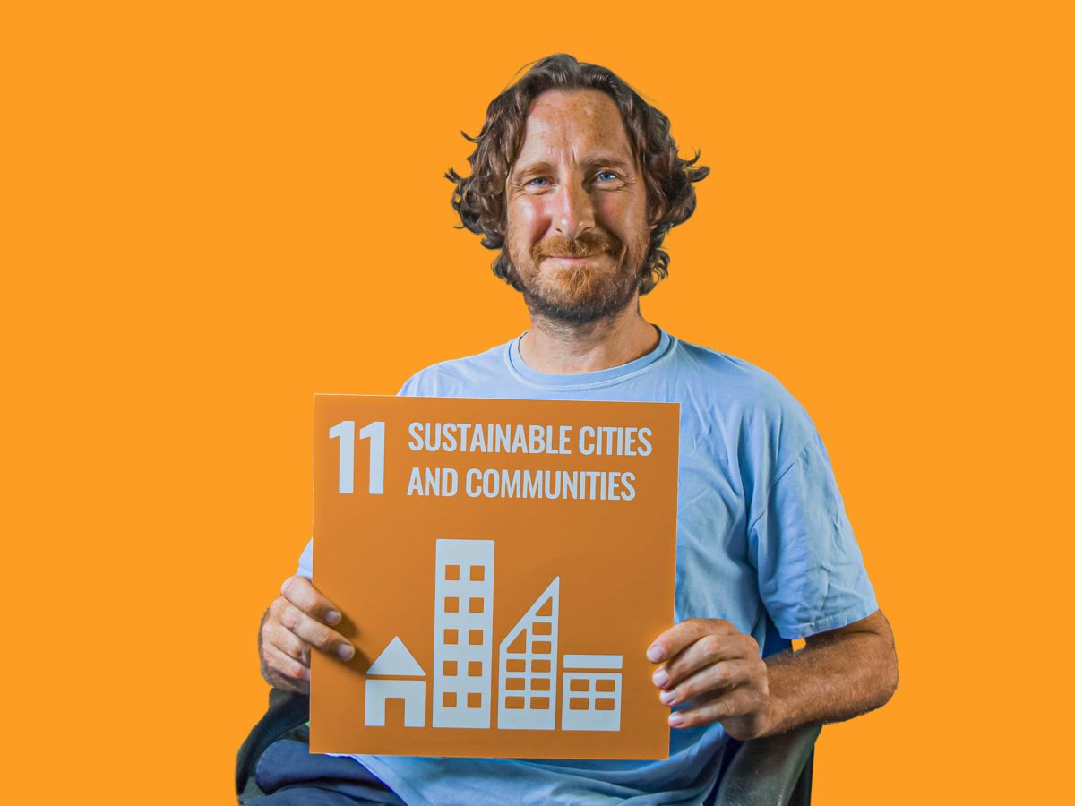Man holding up sign showing Global Sustainable Development Goal 11, sustainable cities and communities.