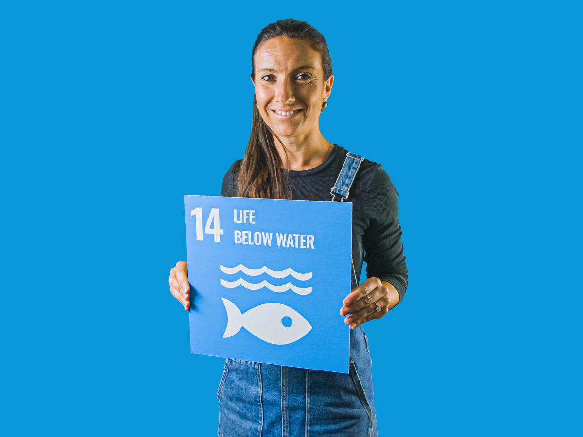 Woman holding up sign showing Global Sustainable Development Goal 14, life below water.