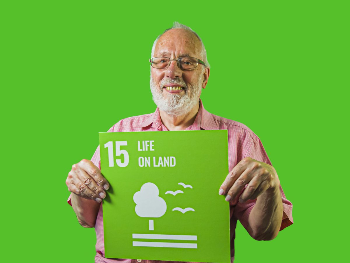 Man holding up sign showing Global Sustainable Development Goal 15, life on land.