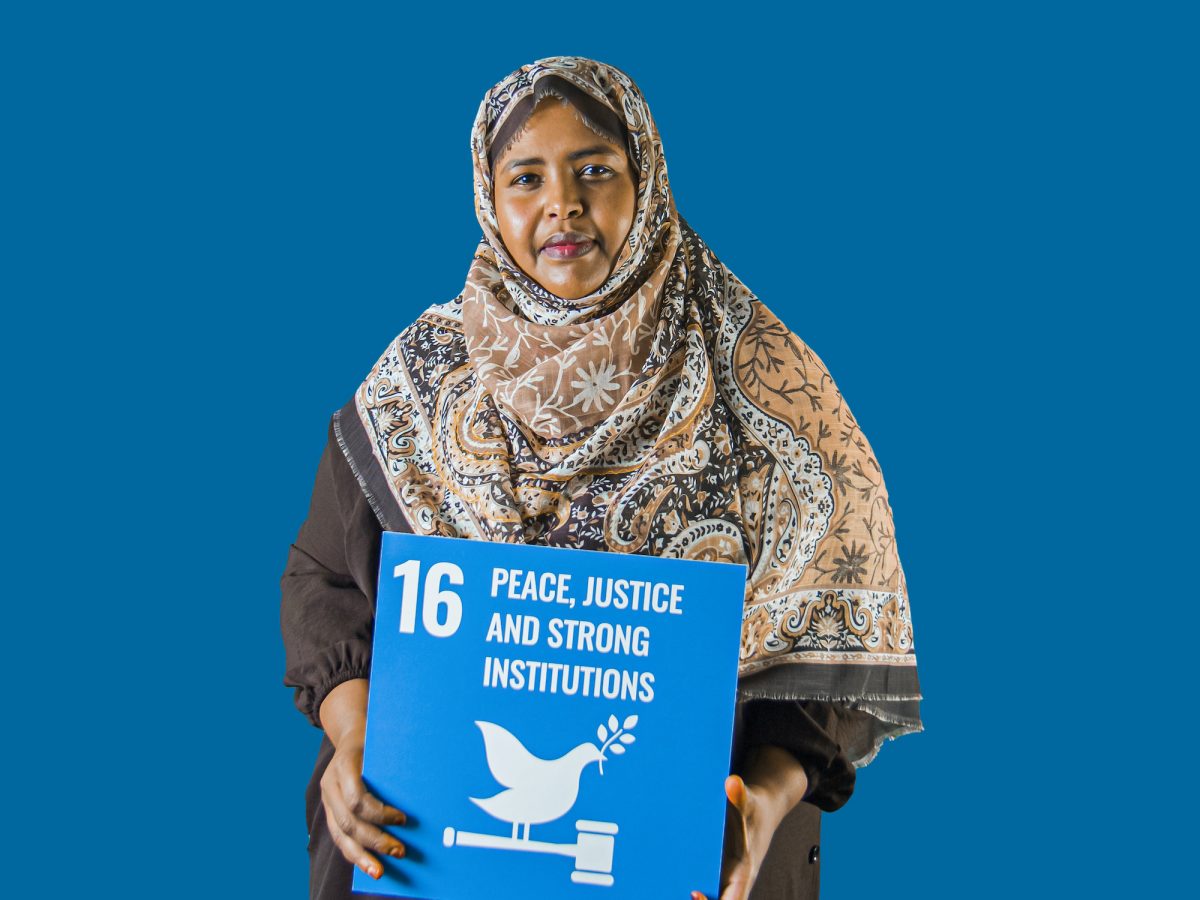 Woman holding up sign showing Global Sustainable Development Goal 16, peace, justice and strong institutions.