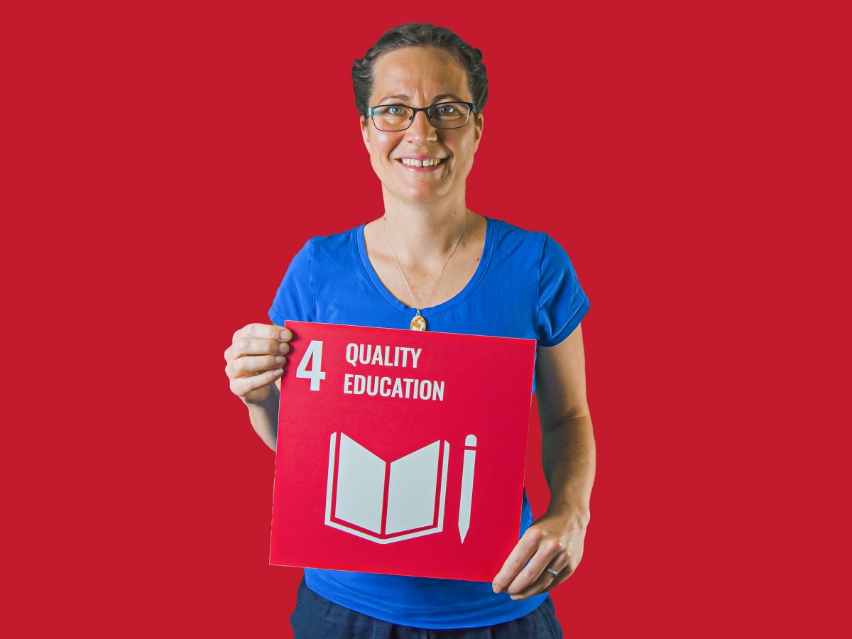 Woman holding up sign showing Global Sustainable Development Goal 4, quality education.