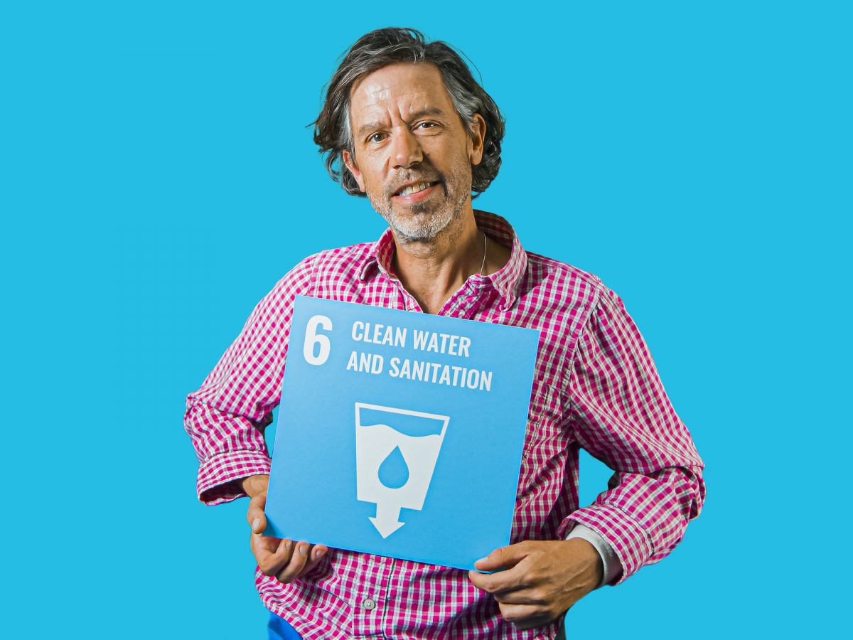 Man holding up sign showing Global Sustainable Development Goal 6, clean water and sanitation.