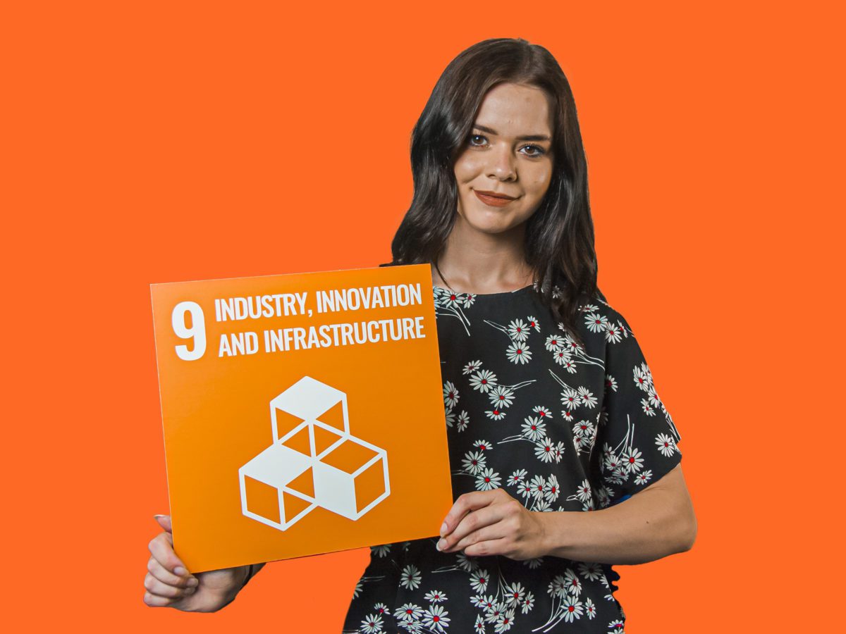 Woman holding up sign showing Global Sustainable Development Goal 9, industry, innovation and infrastructure.