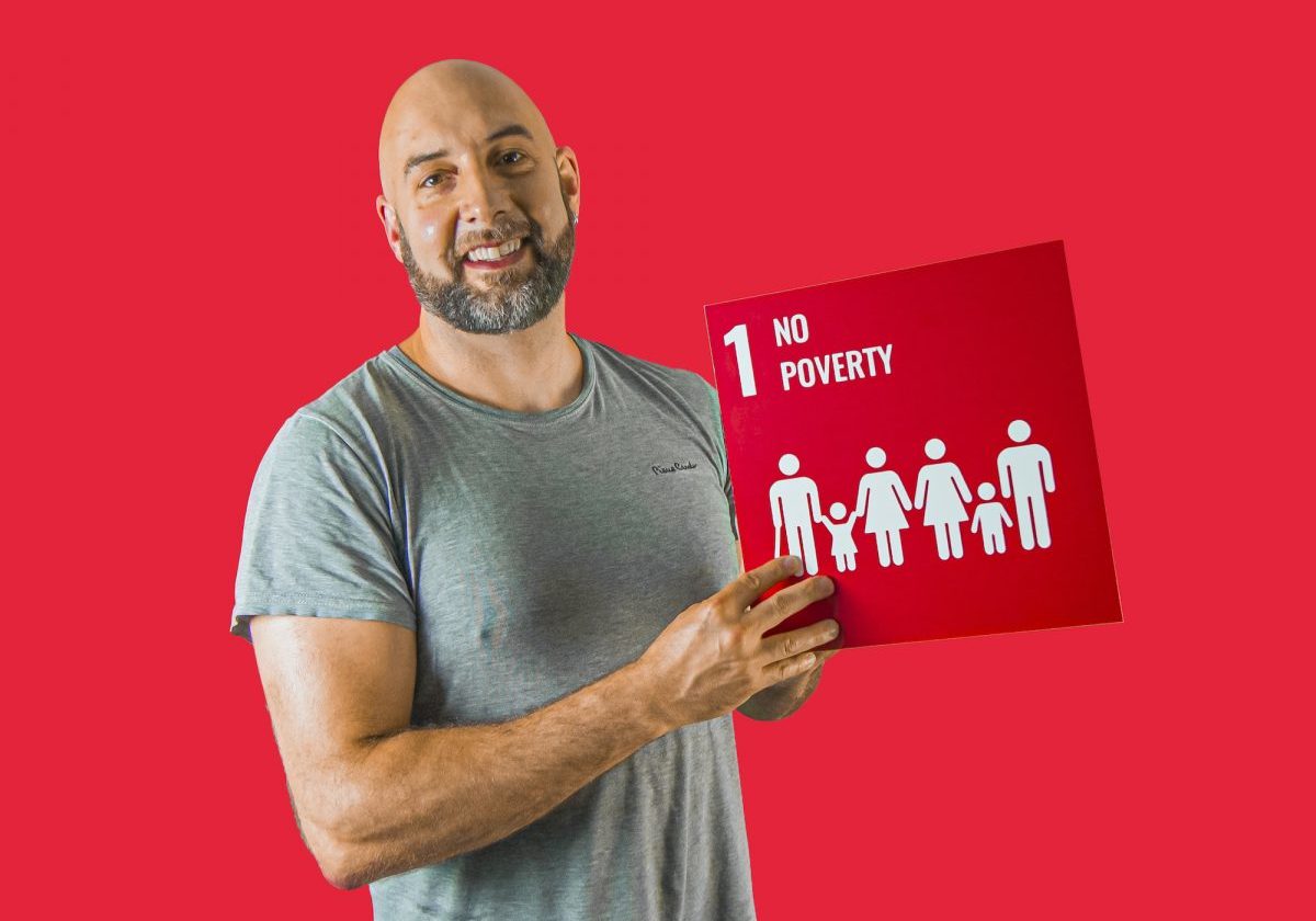 Man holding up sign showing Global Sustainable Development Goal 1, no poverty.