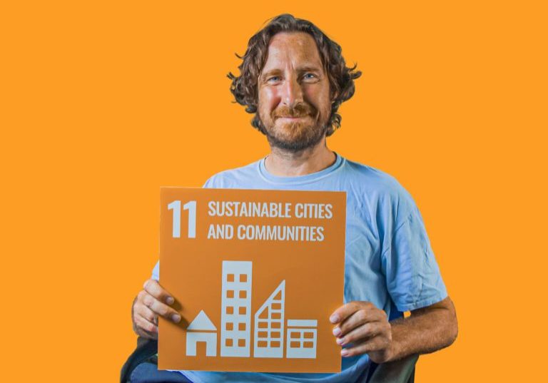Man holding up sign showing Global Sustainable Development Goal 11, sustainable cities and communities.