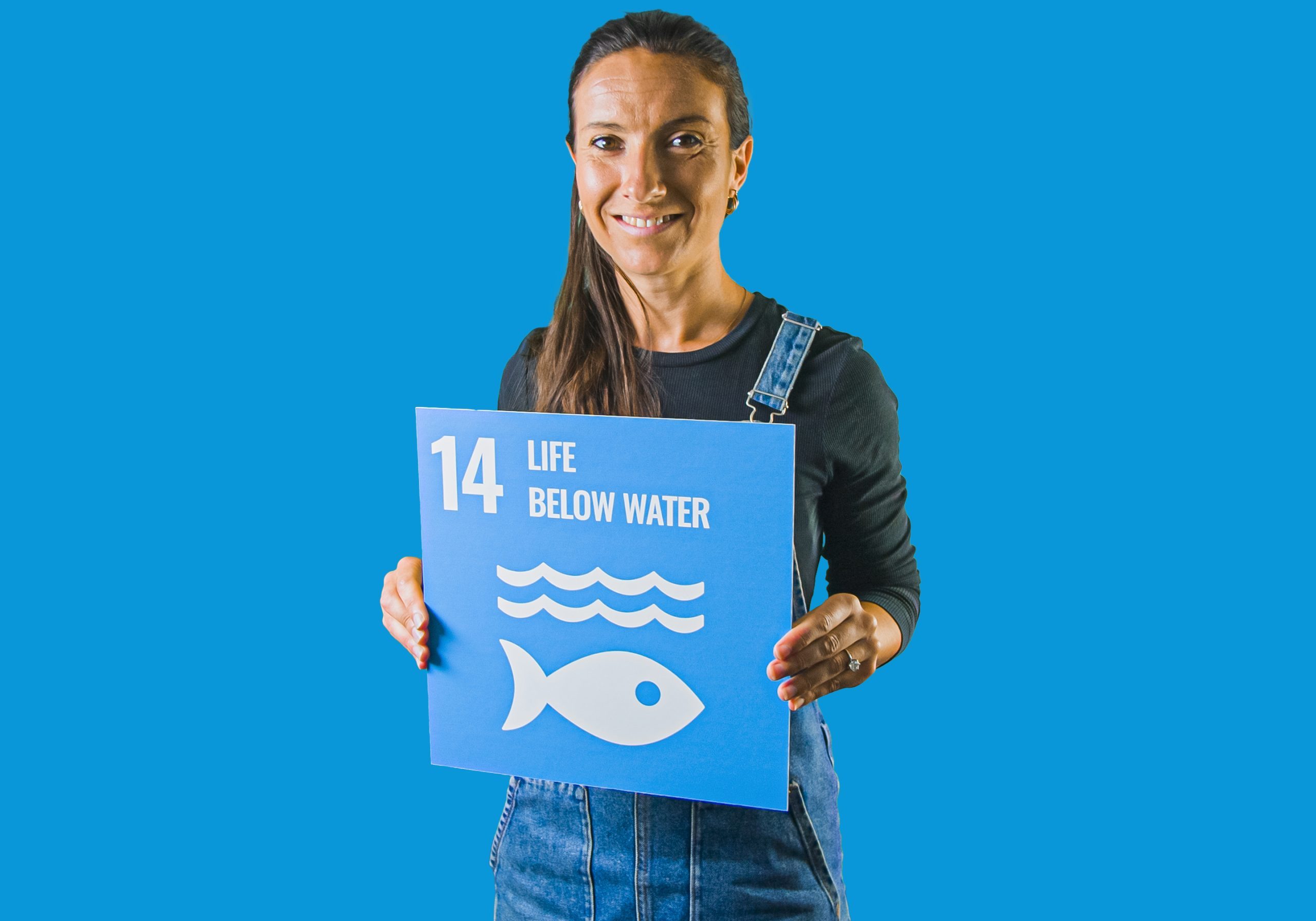 Woman holding up sign showing Global Sustainable Development Goal 14, life below water.