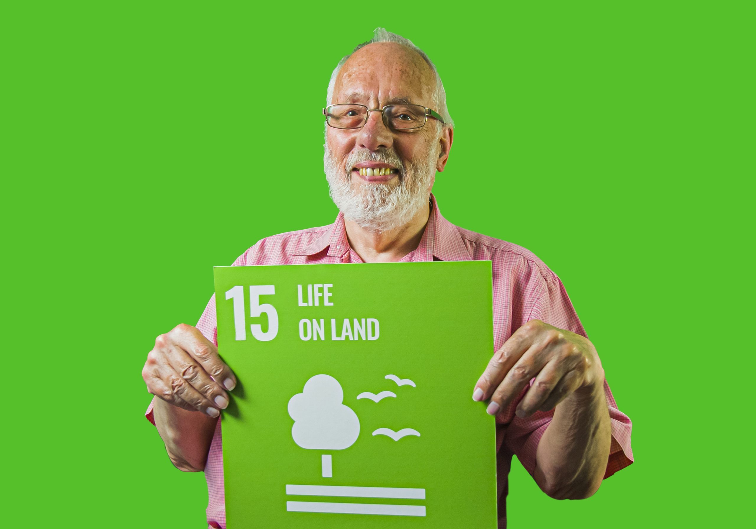 Man holding up sign showing Global Sustainable Development Goal 15, life on land.