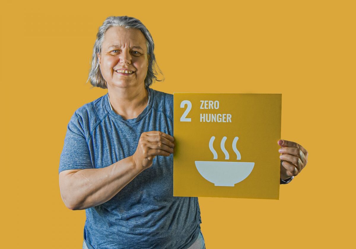Woman holding up sign showing Global Sustainable Development Goal 2, zero hunger.