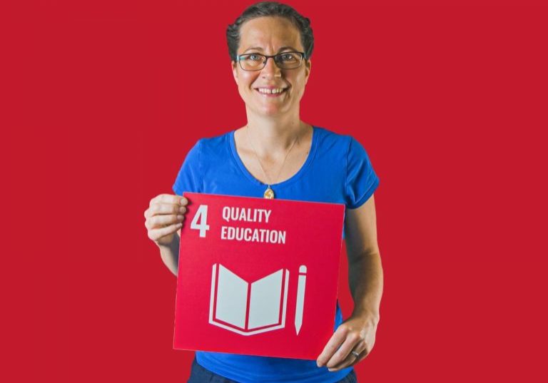 Woman holding up sign showing Global Sustainable Development Goal 4, quality education.