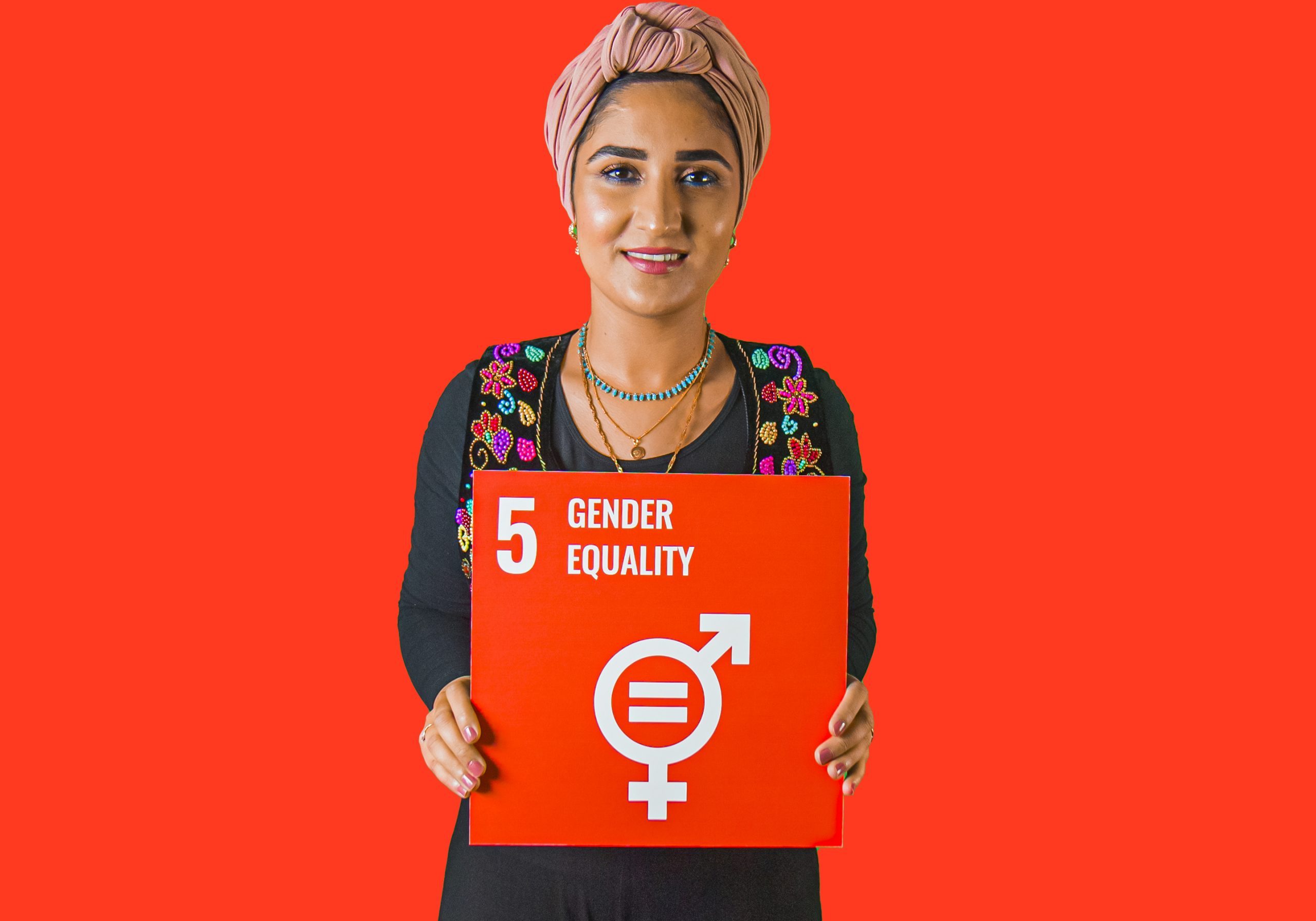 Woman holding up sign showing Global Sustainable Development Goal 5, gender equality.