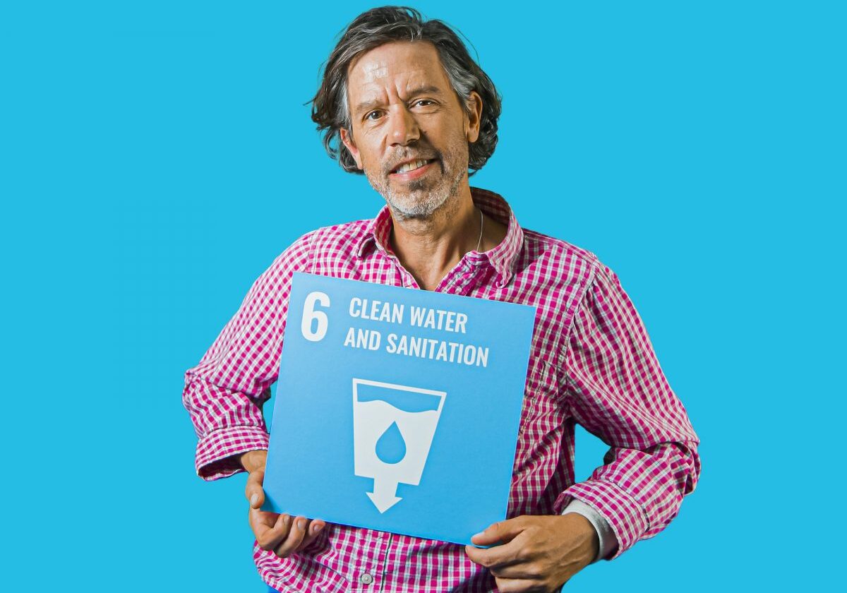 Man holding up sign showing Global Sustainable Development Goal 6, clean water and sanitation.