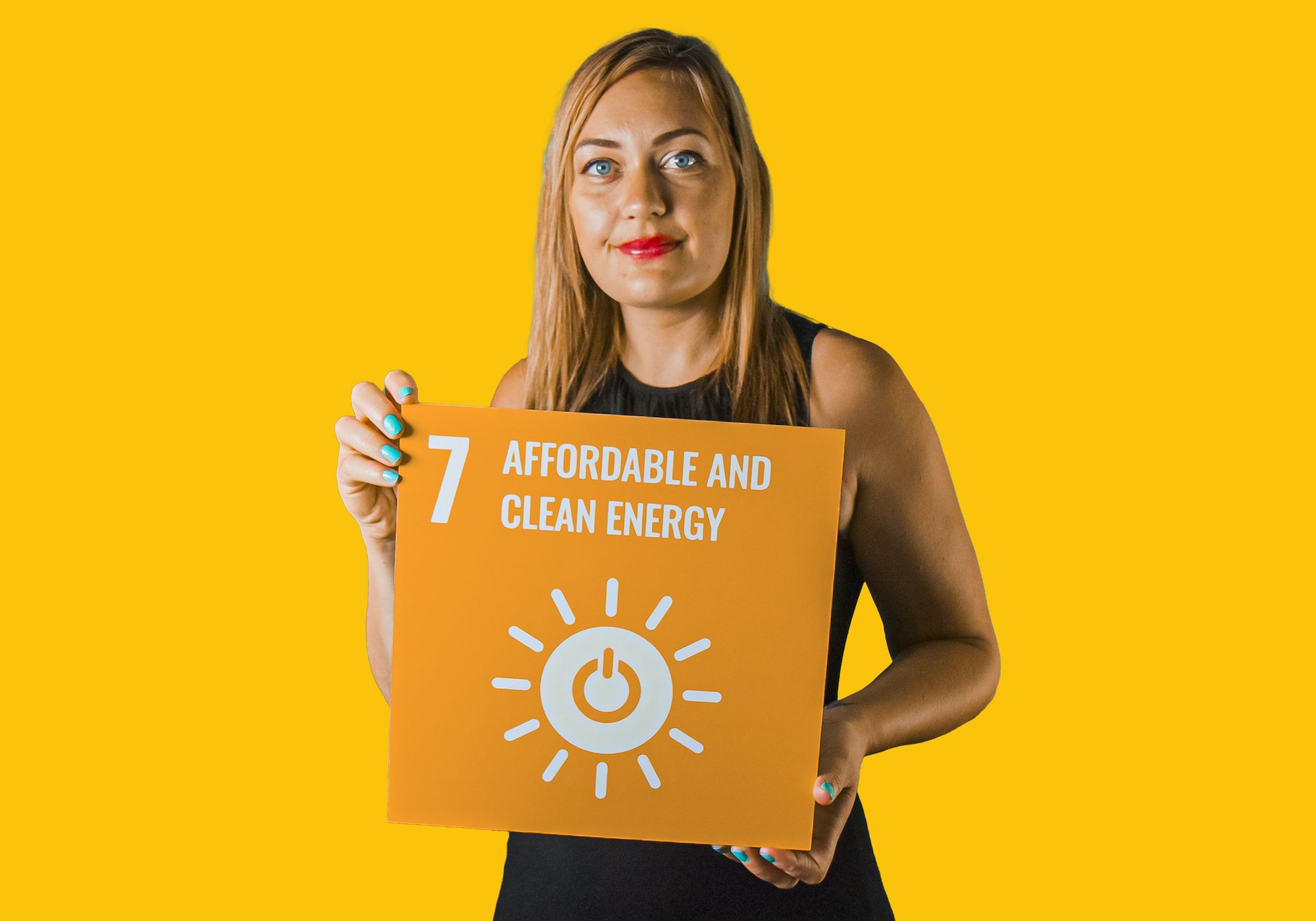 Woman holding up sign showing Global Sustainable Development Goal 7, affordable and clean energy.