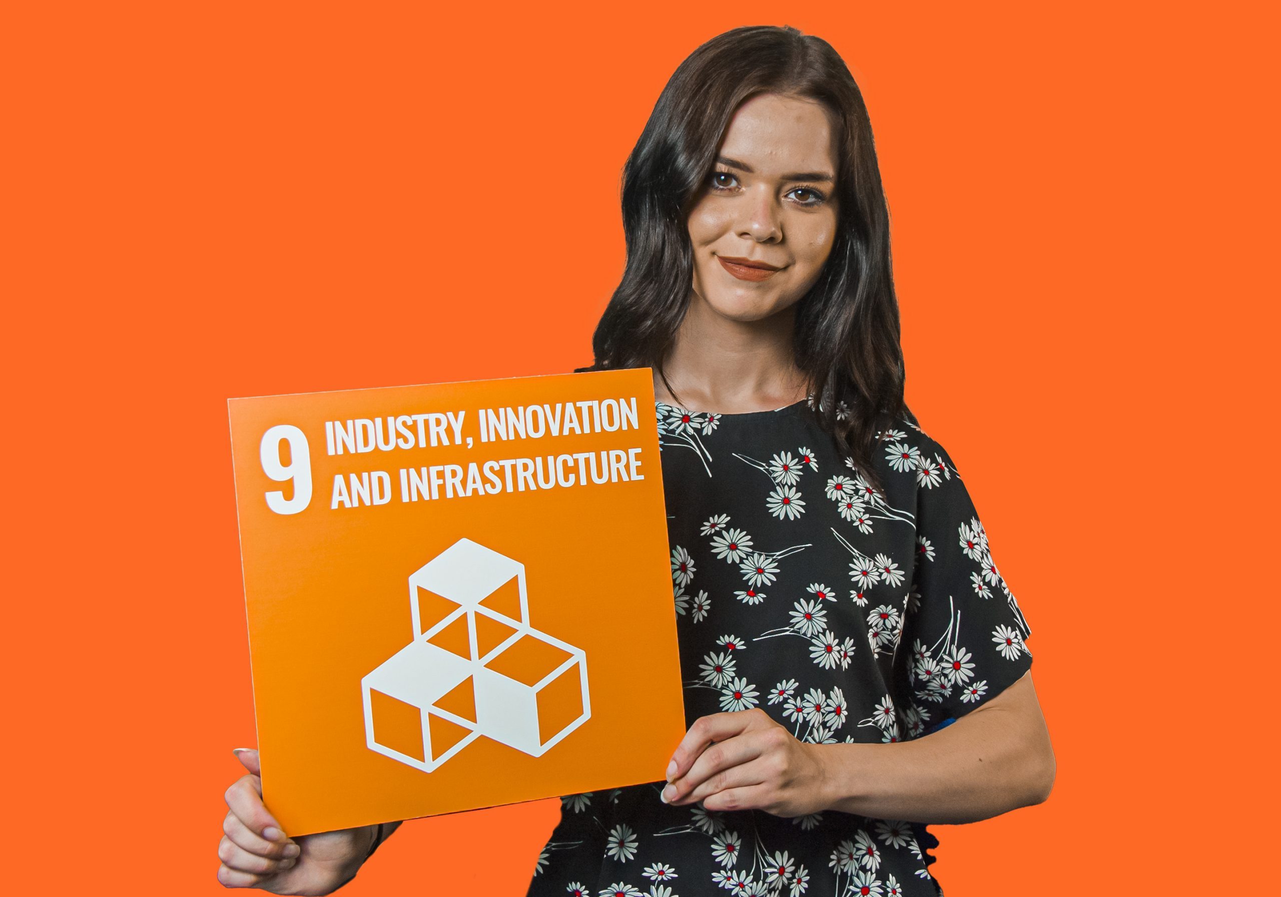Woman holding up sign showing Global Sustainable Development Goal 9, industry, innovation and infrastructure.